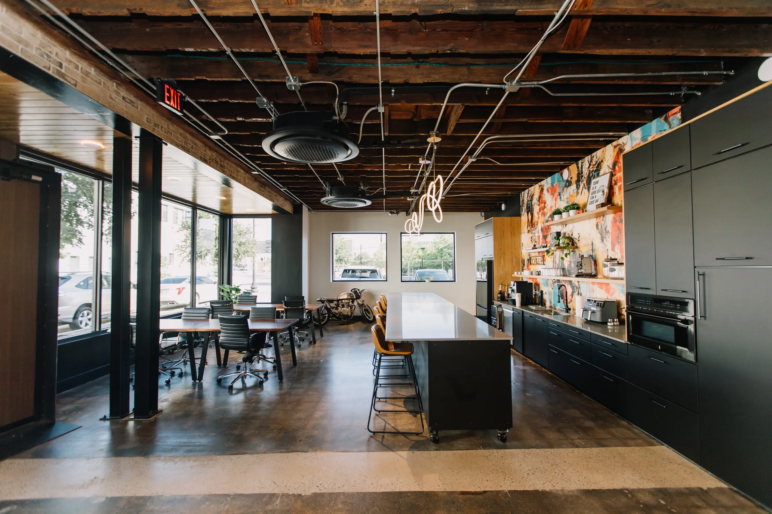 The coworking area with window tables, the coffee bar and exposed wood ceiling