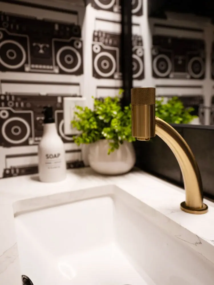A brass faucet in front of boombox wallpaper