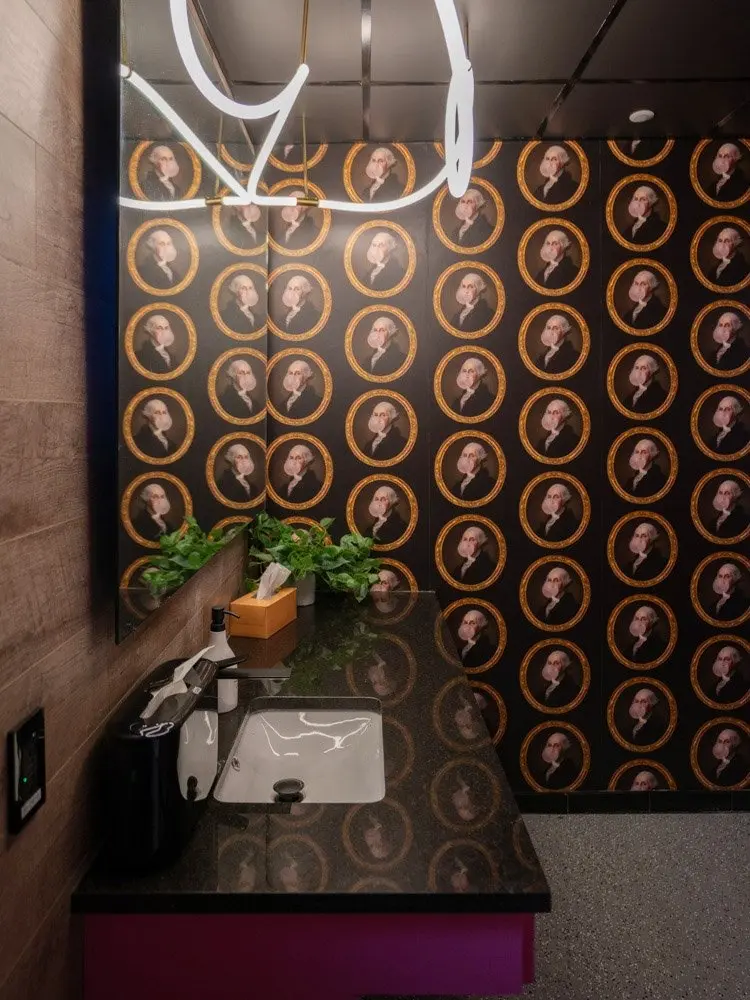 A restroom with portrait wallpaper and a neon light