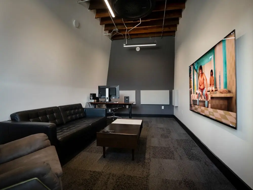 The edit bay with a couch, coffee table and large wall display