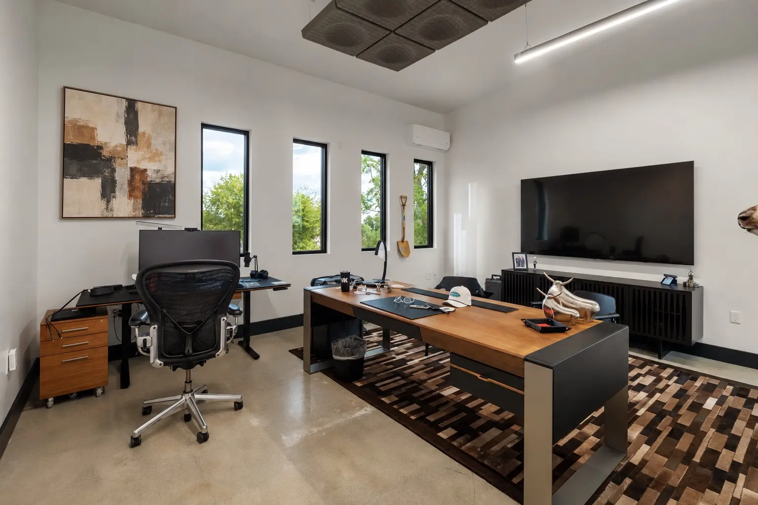 A private office with a large desk, wall display and a row of windows